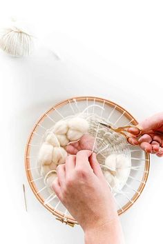 two hands are working on a basket with yarn