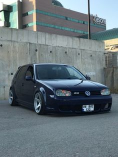 a blue car parked in front of a concrete wall