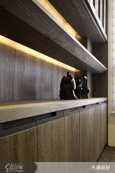 a shelf with two figurines on it in front of a window and some bookshelves