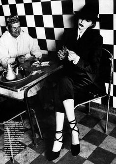 a man and woman sitting at a table playing cards with each other in front of a checkered wall