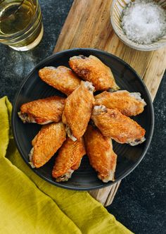 fried chicken wings on a black plate with salt and pepper