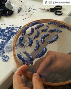 a person is working on something with blue thread and scissors in front of a mirror