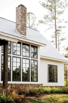 a white house with lots of windows and a stone chimney