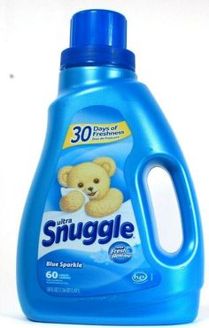 a blue bottle of snuggle on a white surface with a teddy bear in it