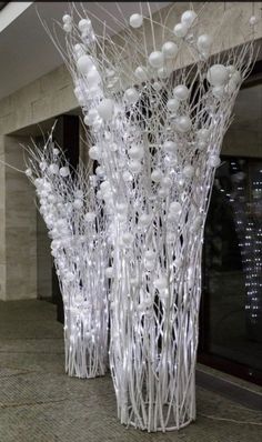 two tall white vases sitting on top of a stone floor next to each other