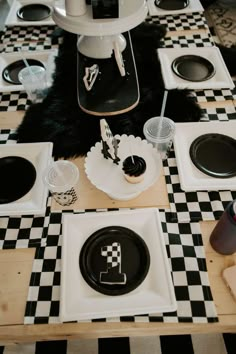 black and white checkered table cloth with plates, cups, utensils and napkins