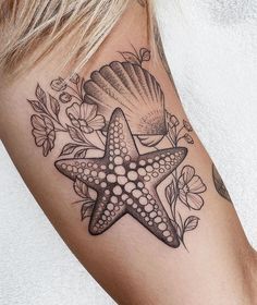 a starfish and seashell tattoo on the right side of the left arm with flowers around it