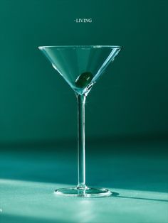 a martini glass sitting on top of a table next to a green background with the words living