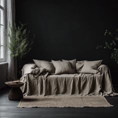 a couch sitting in front of a window next to a potted plant on top of a table