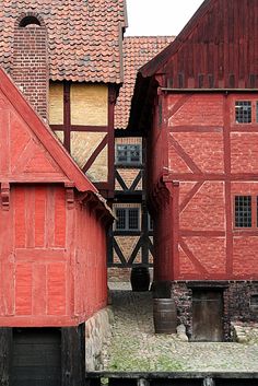 an old red brick building with a clock on it's side and two other buildings in the background