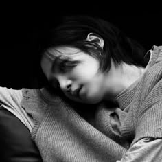 a woman laying on top of a black couch next to a wall with her eyes closed