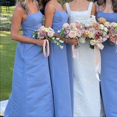 three bridesmaids in blue dresses holding bouquets of flowers on their wedding day