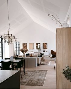 a living room filled with furniture and a chandelier hanging from the ceiling over a dining table