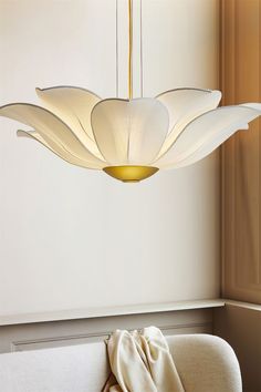 a modern light fixture hanging from the ceiling in a room with white walls and furniture