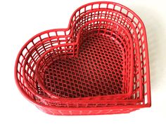 a red heart shaped basket sitting on top of a table