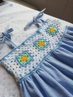 a crocheted blue and white blanket on top of a bed next to a cross