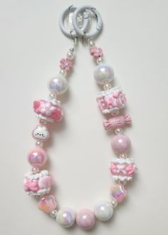 a pink and white beaded necklace with hello kitty charms hanging from it's side