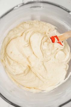 a mixing bowl filled with white batter and a wooden spatula in the bottom right corner