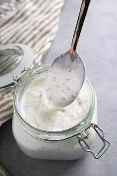 a spoon full of yogurt sitting on top of a glass jar filled with liquid