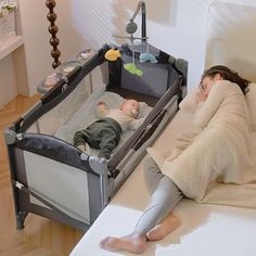 a woman laying in bed next to a baby crib