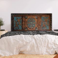 the bed is made up with white linens and an intricate wooden headboard on it