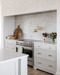 a kitchen with white cabinets and gold pulls on the handles, brass knobs and an oven