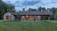 a house in the middle of a field with grass and trees around it at dusk