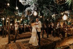 a bride and groom are dancing in the middle of an outdoor venue with disco balls hanging from the ceiling