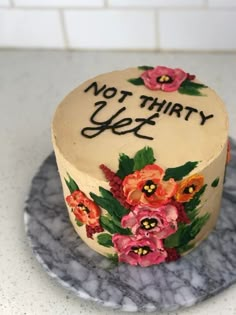 there is a cake that has been decorated with flowers and words on it, but not thirty yet