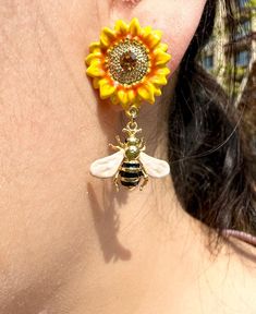 These handmade earrings are a true work of art, combining an asymmetrical design with sunflower inspiration. Each pair of earrings is carefully crafted by experienced craftsmen using exquisite sealed enamel techniques, presenting stunning details and exquisite craftsmanship. Each earring has a unique asymmetrical shape for a chic yet stylish style that will make you stand out from the crowd. The sunflower pattern is beautifully interpreted in the earrings, bringing sunshine-like vitality and joyful mood to the wearer. Whether paired with a casual outfit or a formal dress, these earrings will add a unique accent to your look. Whether as a reward for yourself or as a gift to a loved one, these earrings are the perfect choice to express your taste and personality. PACKING Free Dainty Gift Box Sunflower Inspiration, Enamel Techniques, Bee Flower, Lover Jewelry, Sunflower Jewelry, Asymmetrical Earrings, Sunflower Earrings, Bee On Flower, The Sunflower