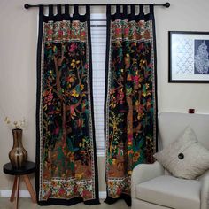 a living room with a white chair and black curtains in front of a window that has an animal design on it