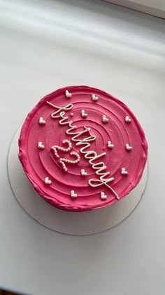 a birthday cake with pink frosting and hearts on it