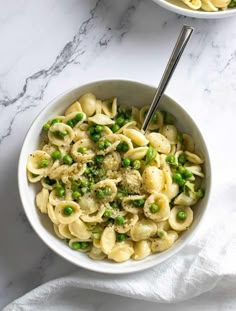 two bowls filled with pasta and peas on top of a table