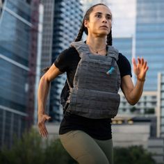 a woman running in the city with her back pack strapped to her chest and hands out