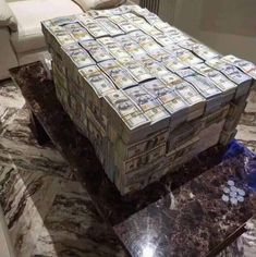 a large stack of money sitting on top of a marble table next to a couch