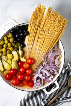 a bowl filled with pasta, olives, onions and tomatoes