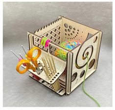 a wooden box with scissors and yarn in it