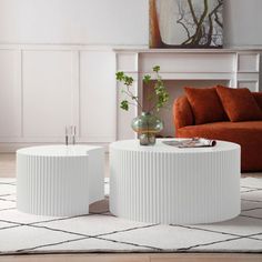 two white tables sitting on top of a rug in front of a couch and coffee table