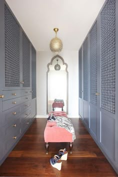 a bed sitting in the middle of a hallway next to blue cabinets and drawers with shoes on them