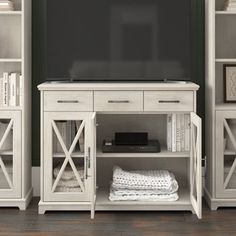 a white entertainment center with bookshelves and a flat screen tv