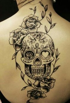 a woman's back with a skull and roses tattoo on it