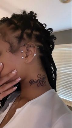 a close up of a person with ear piercings on her neck and hand in front of her face