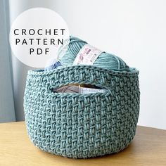 a large blue basket sitting on top of a wooden table next to a ball of yarn