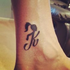 a person with a tattoo on their foot that has the letter k in black ink