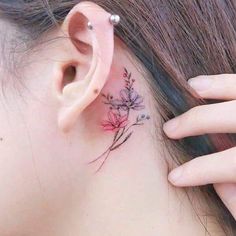 a close up of a person's ear with flowers behind her ear and behind the ear tattoo