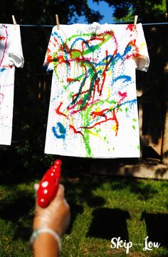 two shirts hanging on a clothes line with paint splattered on them