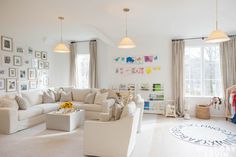 a living room filled with white furniture and lots of pictures on the wall behind it