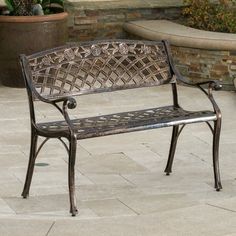 a metal bench sitting on top of a stone floor next to a potted plant