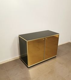 a black and gold cabinet sitting on top of a floor next to a white wall