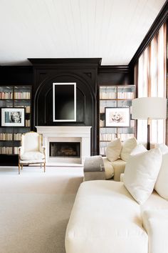 a living room filled with lots of white furniture and bookshelves next to a fire place